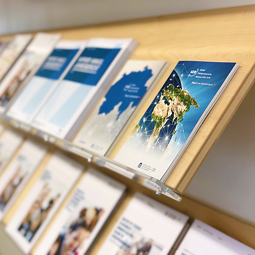 Closed brochures displayed on a shelf – HEG Fribourg